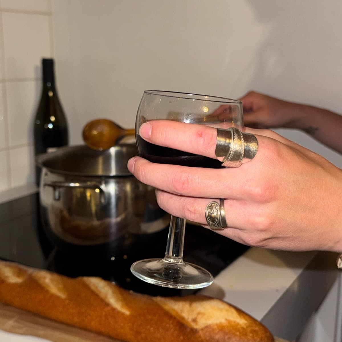 Spoon rings on a hand holding a glass of red wine
