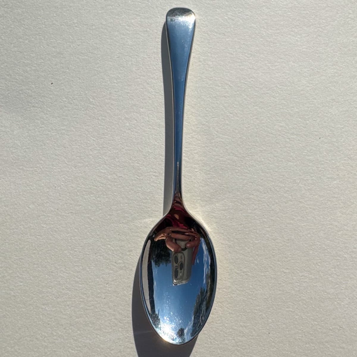 A polished silver teaspoon on white paper